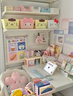 a white desk topped with lots of toys next to shelves filled with books and other items