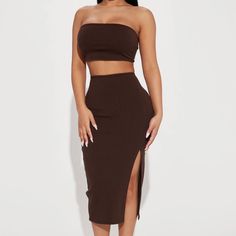 a woman wearing a brown two piece skirt and crop top with one slit down the side