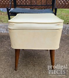 an upholstered chair sitting on top of a gravel ground next to a fence