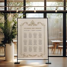 a table plan is displayed in front of a large window with potted plants on it