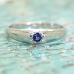 a close up of a ring with a blue stone in it on a marble surface