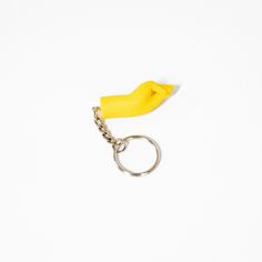 a banana shaped keychain with a chain attached to it on a white surface