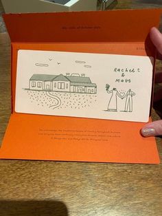 a person holding up an orange card with a drawing on it