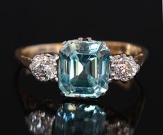 Vintage mid 1900's blue zircon and diamond gold ring set with a cushion cut natural blue zircon to the centre and two old cut natural diamonds (0.1 carat each) on the sides onto an 18k yellow gold band. The central zircon measures 6.9 by 6.2 weighing 1.78 karats. This attractive stone is in a vivid greenish blue colour with very good clarity. Diamonds: very bright and white with H/I color and VS clarity The shank is stamped 18 for 18k gold. Size: 5 (US), J1/2 (UK) finger size.  Please select the Blue Zircon Ring, Bridal Diamond Ring, Gold Gallery, Diamond Gold Ring, Diamond Ring Settings, Gold Ring Sets, Ring Ideas, Natural Diamond Engagement Ring, Greenish Blue