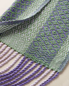 a purple and green knitted blanket laying on top of a table