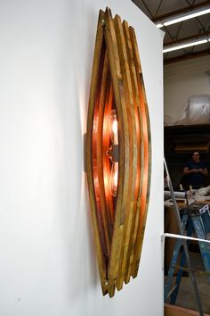 a wooden light fixture mounted on the side of a wall next to a man working