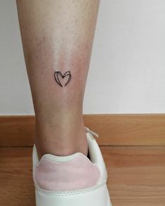 a small heart tattoo on the ankle is shown in black ink, with an arrow at the center