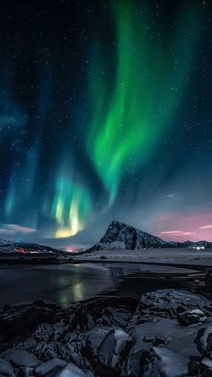 the aurora lights shine brightly in the night sky over an icy lake and mountain range