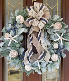 a wreath on the front door with flowers and seashells hanging from it's side