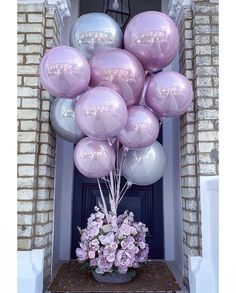 a bunch of balloons that are in the air on a front door with pink flowers