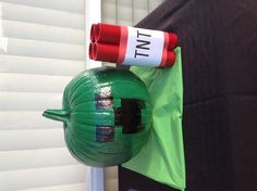 a green pumpkin sitting on top of a table next to a red tube and marker