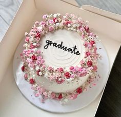 a white cake with pink flowers and the word graduate written on it in black lettering