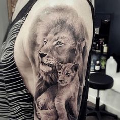 a woman with a lion and cub tattoo on her arm, in black and white