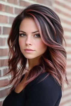 Woman with wavy brown and pink-highlighted hair standing against a brick wall. Coloured Hair Ideas Brunettes, Merlot Bayalage Hair, Brunette Hair With Burgundy Money Piece, Hair Peekaboo Color Brunettes, Peek A Boo Hair Color Brown, Best Hair Color Ideas For Brunettes, Money Pieces For Dark Hair, Ref Balayage, Stunning Hair Color