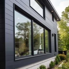 an exterior view of a house with black siding and large windows on the side of it