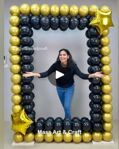 a woman standing in front of a balloon frame with gold and black balloons on it