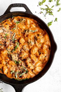 a skillet filled with macaroni and cheese on top of a white table