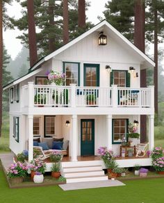 a white house with green shutters and flowers on the front porch is surrounded by tall pine trees