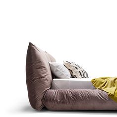 a couch with pillows on top of it in front of a white wall and floor