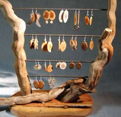 a wooden sculpture with earrings hanging from it's sides and a tree branch on the other side