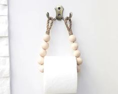 a roll of toilet paper hanging on a wall with two wooden beads attached to it