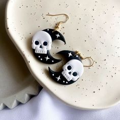 pair of skull and crescent moon earrings on white plate