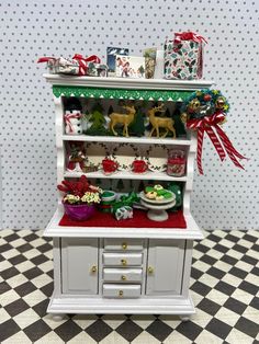 a dollhouse kitchen with christmas decorations on the top shelf and shelves above it,