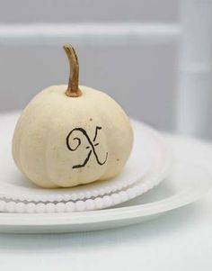 a small white pumpkin with the letter k on it's side sitting on a plate