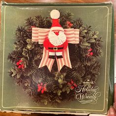 an old fashioned christmas card with a santa clause on it's head and wreath