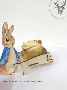 a cupcake in a wooden cart with a rabbit figurine next to it