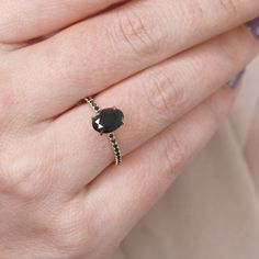 a woman's hand wearing a ring with a black stone on the middle finger