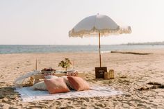 an umbrella and some pillows on the beach