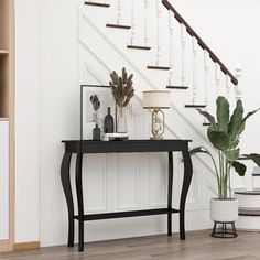 a living room with a black table and white stairs next to a potted plant