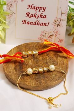 two bracelets with pearls are sitting on a wooden plate next to a greeting card