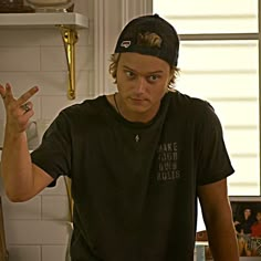 a young man making the peace sign while standing in front of a kitchen counter top