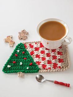 a crocheted christmas tree coaster next to a cup of coffee