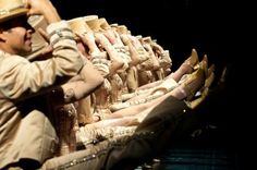 a man sitting on top of a boat filled with lots of women's shoes