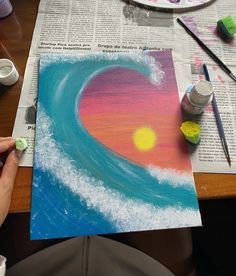 someone is painting a heart in the sky with watercolors on paper and paintbrushes