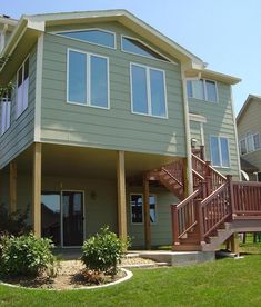 a house with stairs leading up to the second floor and another building in the background