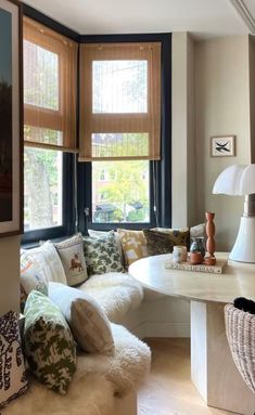 a living room filled with lots of furniture next to a window covered in blinds and pillows