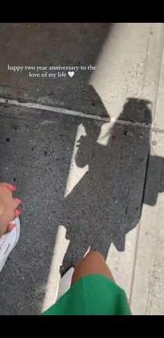 the shadow of a person standing next to a street with a sign that says happy two year anniversary to the love of my life