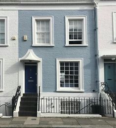 a blue and white house with stairs leading up to the front door on a city street