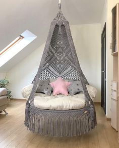 a bedroom with a hammock hanging from the ceiling and pillows on the bed