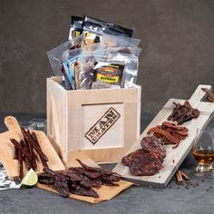 a wooden box filled with assorted meats next to a glass of wine and snacks