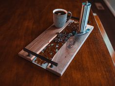 a wooden tray with a cup of coffee on top of it next to a grinder