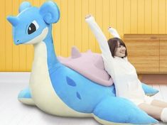 a woman sitting on top of a giant blue and white dragon pillow in a room