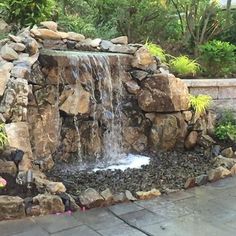 a rock waterfall in the middle of a garden