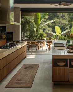 an open kitchen and dining area with wooden cabinets, counter tops, and floor to ceiling windows