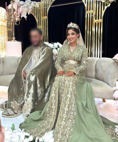 the bride and groom are sitting on a couch in their wedding outfits, posing for a photo