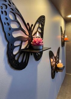 a wall mounted candle holder with two butterflies on it and candles in the corner next to it